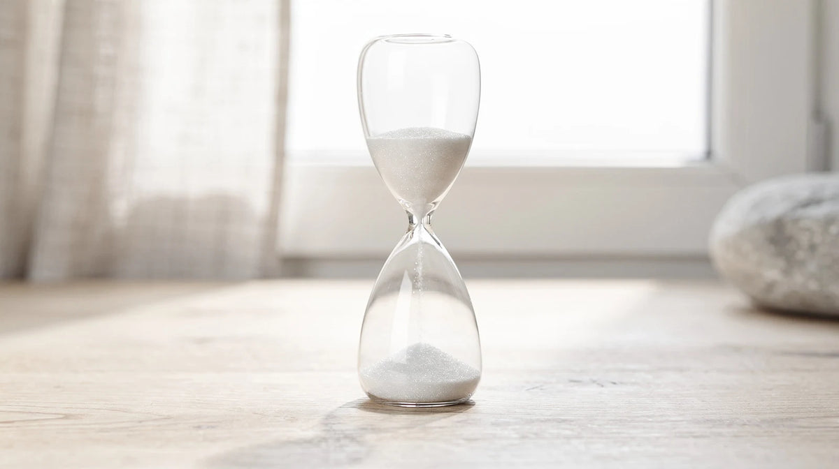 THCA Wirkung: Sanduhr aus Glas auf hellem Holz als Sinnbild für Zeit und Untersuchung
